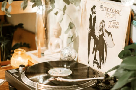 Vintage record player styled on a wooden surface with warm lighting, greenery, and classic 1970s retro decor accents.