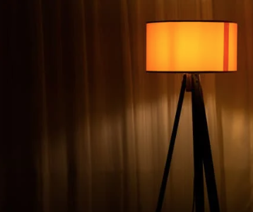 Minimalist floor lamp with a warm amber shade creating soft, moody lighting inspired by 1970s interiors.